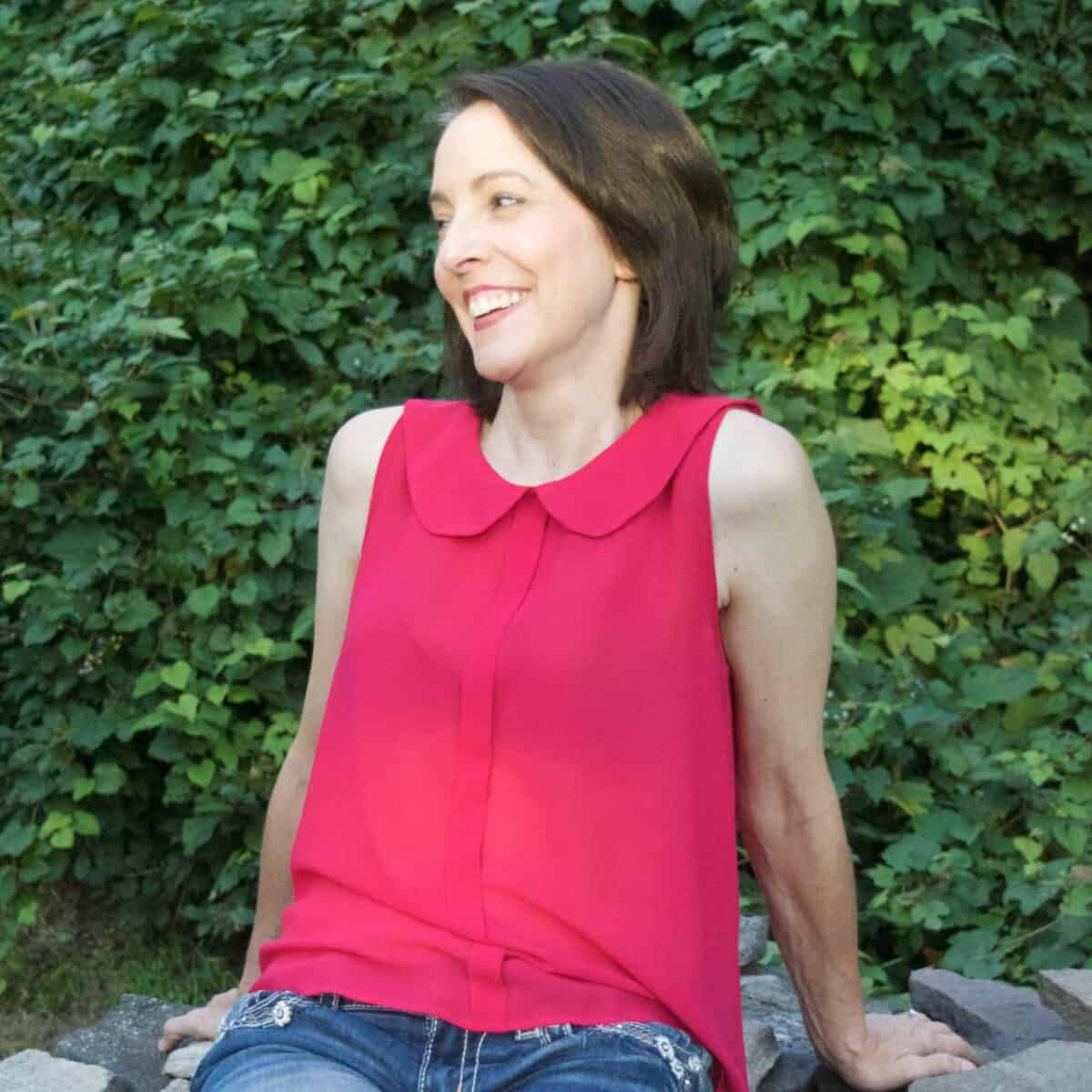About me photo of author of Artsy Pretty Colors, Ellen. Sitting on rocks, smiling.